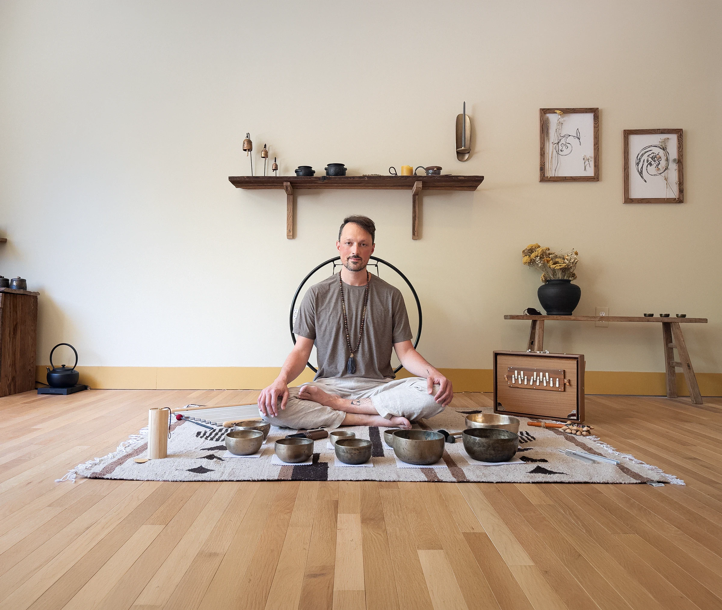 Matias seated cross-legged behind a row of singing bowls